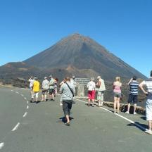 a group of people walking down a road with a mountain in the background