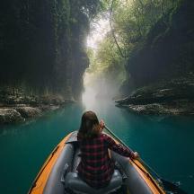 eine Frau paddelt mit einem Kanu einen Fluss hinunter