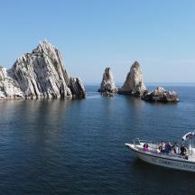 a group of people on a boat in the water with rocks