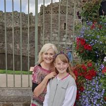 a woman and a young girl standing in front of flowers
