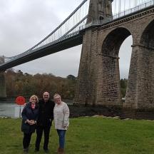 a group of three people standing in front of a bridge