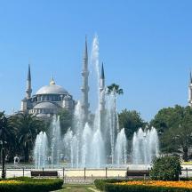 a fountain in front of a building with two blue mosques
