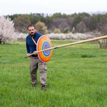 a man holding a spear and a target