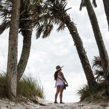 a woman standing on a beach with palm trees