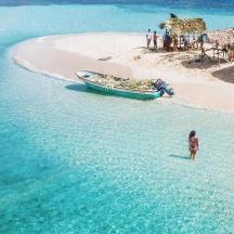 eine Person, die mit einem Boot im Wasser an einem Strand steht