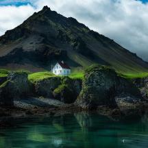 a house on the side of a mountain with water