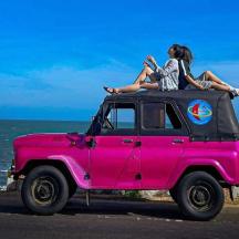 two people sitting on the top of a pink jeep