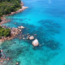 an aerial view of a beach with rocks and blue water