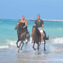 eine Gruppe von Menschen reitet am Strand