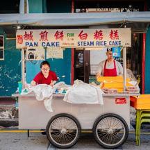 a woman is standing at a food cart