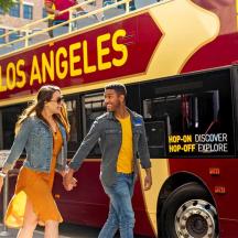 a man and woman walking in front of a bus
