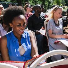 a woman sitting in a crowd with a tennis racket