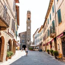 a woman walking down a street with a clock tower
