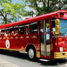 a red bus driving down a street with people inside