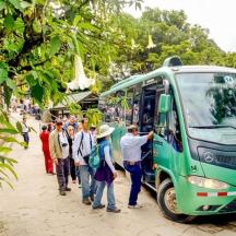 a group of people standing next to a green bus