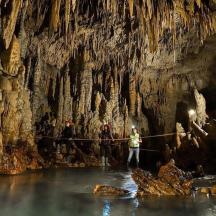 a group of people standing in the water in a cave