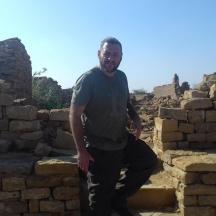 un homme debout devant un mur de briques