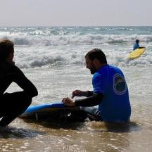 to personer sidder i havet med et surfbræt