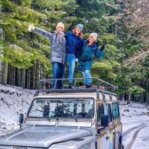 three people standing on the roof of a vehicle in the snow