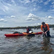 two men standing in the water next to a kayak