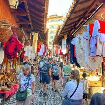 a group of people walking through a market with clothes