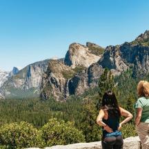 two people standing on a rock looking at a mountain
