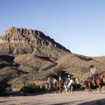 a group of people riding horses in the desert