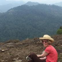a woman in a hat sitting on top of a hill