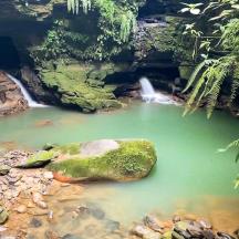 a pool of green water in front of a waterfall