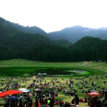 a large crowd of people in a field with mountains