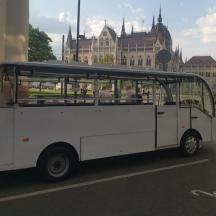 un petit autobús blanc circulant per un carrer de la ciutat