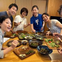 a group of people standing around a table with food