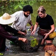 three people in the water with a basket of broccoli