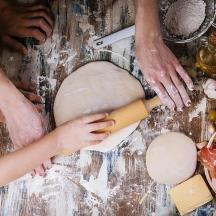 a group of people making a dough on a table