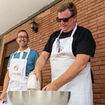 dos homes a la cuina preparant menjar a la taula