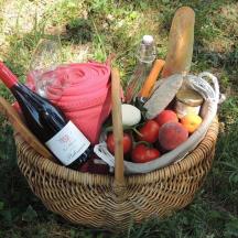 una cistella de fruites i verdures amb una ampolla de vi