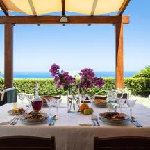 ein Tisch mit Essen und Blumen darauf mit dem Meer im Hintergrund