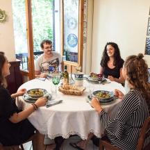 bir masanın etrafında oturup yemek yiyen bir grup insan