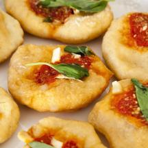 un grup de pizzes petites amb salsa i alfàbrega