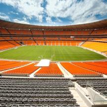 an empty stadium with orange seats and a soccer field