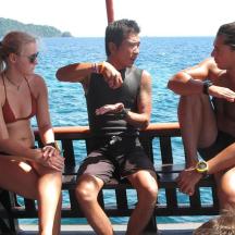 three people sitting on a bench by the water