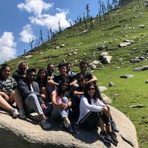 a group of people sitting on a rock on a hill