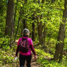 a woman walking on a trail in the woods