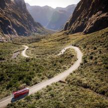 a red car driving down a road in a canyon