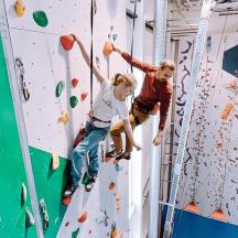 two boys are climbing on a climbing wall
