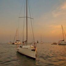 a white sail boat in the water with other boats