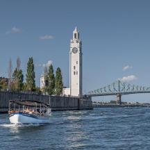 a boat in the water with a clock tower and a bridge