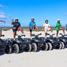 a group of people standing on the beach with atvs