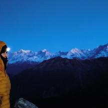 a person in a yellow jacket standing on a mountain