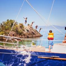 a group of people jumping off a boat in the water